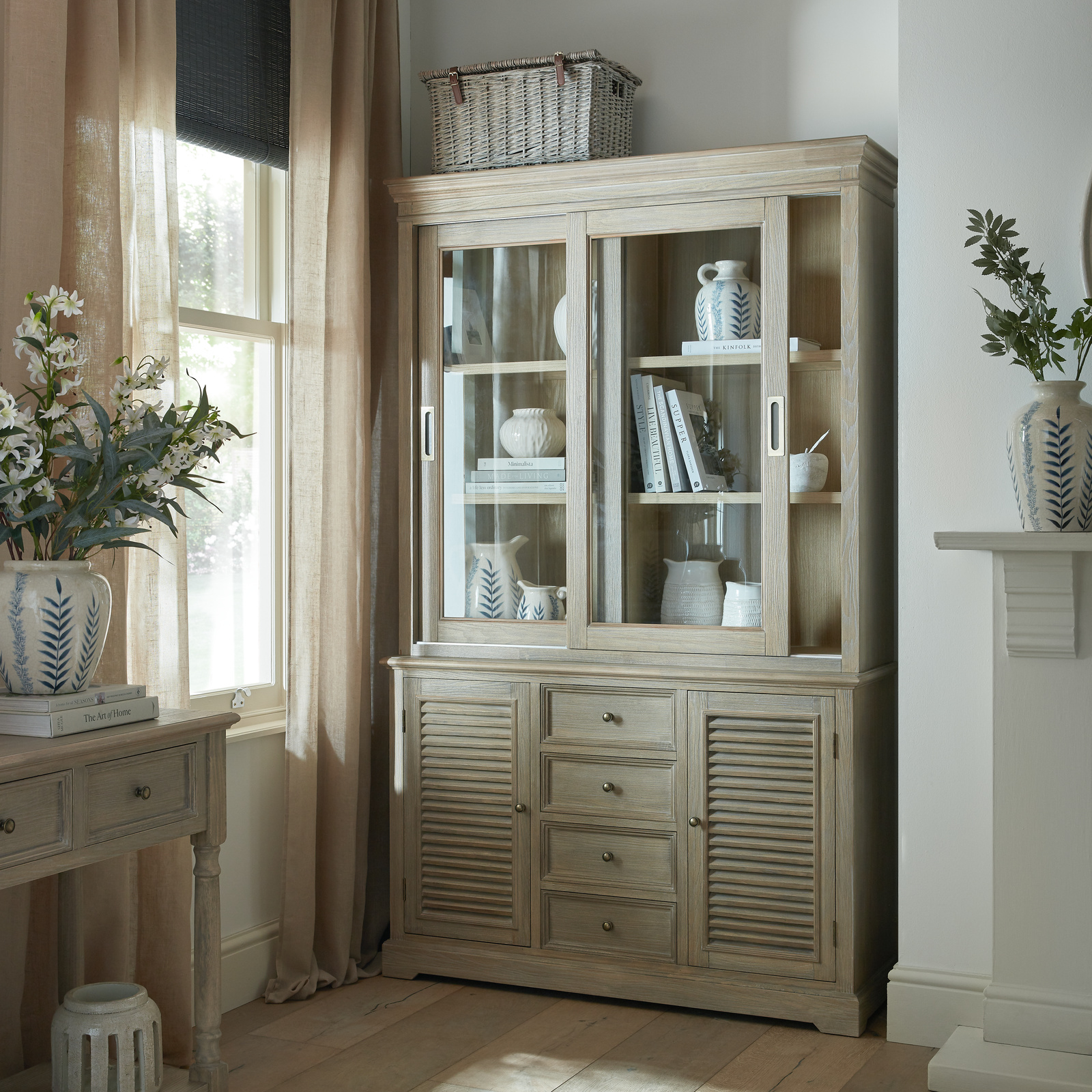 A light wood dresser with two doors and four drawers sits in an alcove in a spacious room, next to a window.