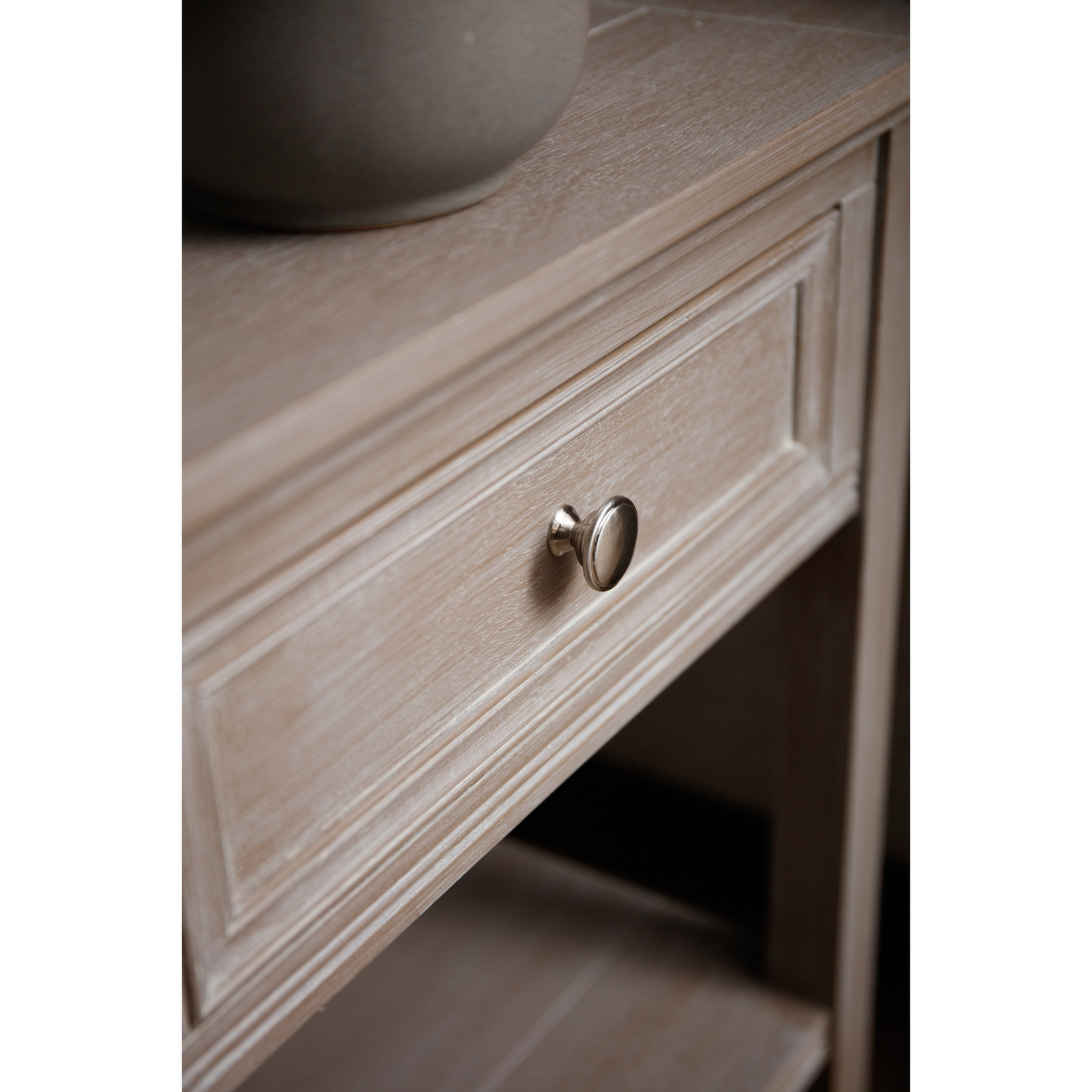 The image shows a close up of the drawer front of a wooden side table.