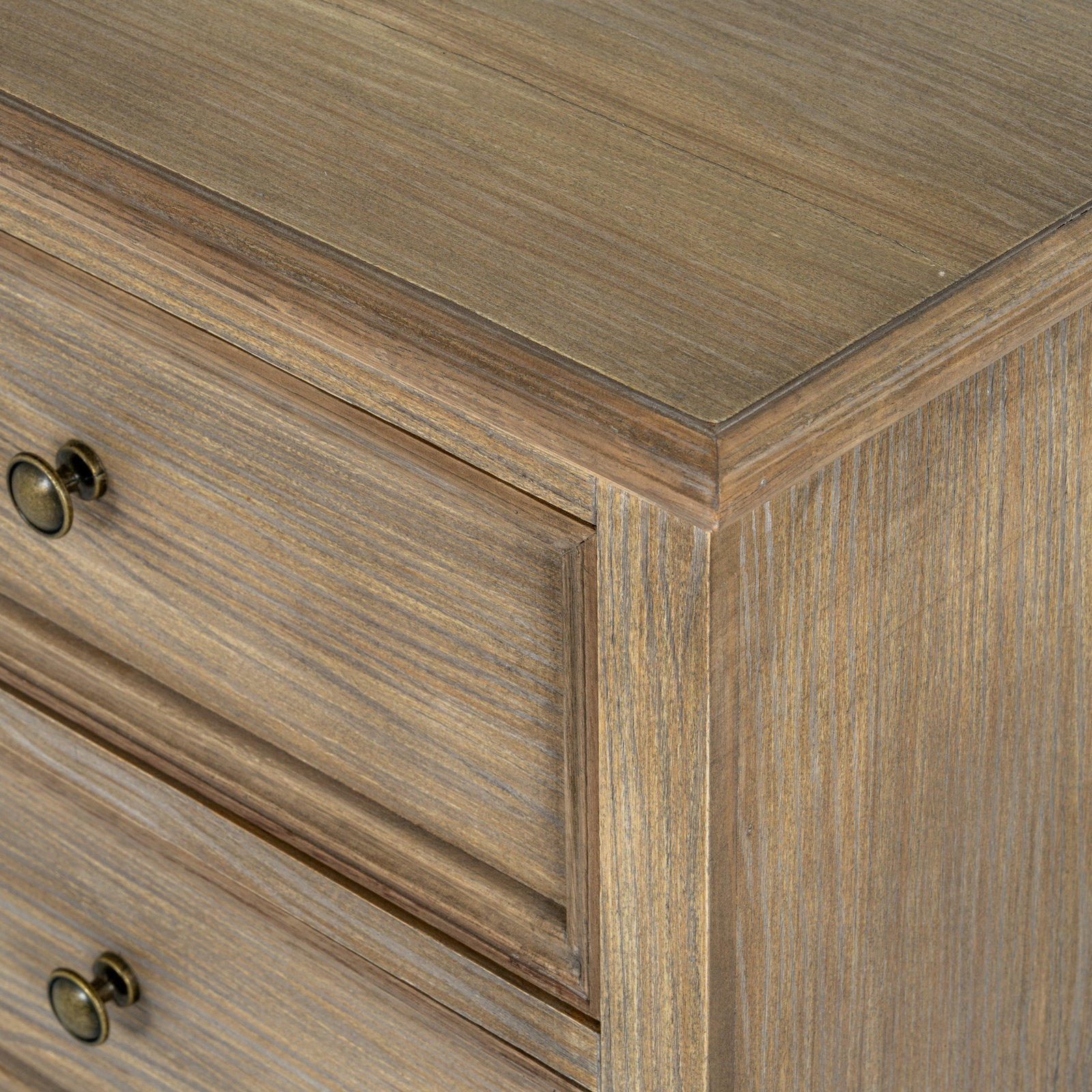 The image shows a close up of the corner detail of a brown wooden bedside table with drawers