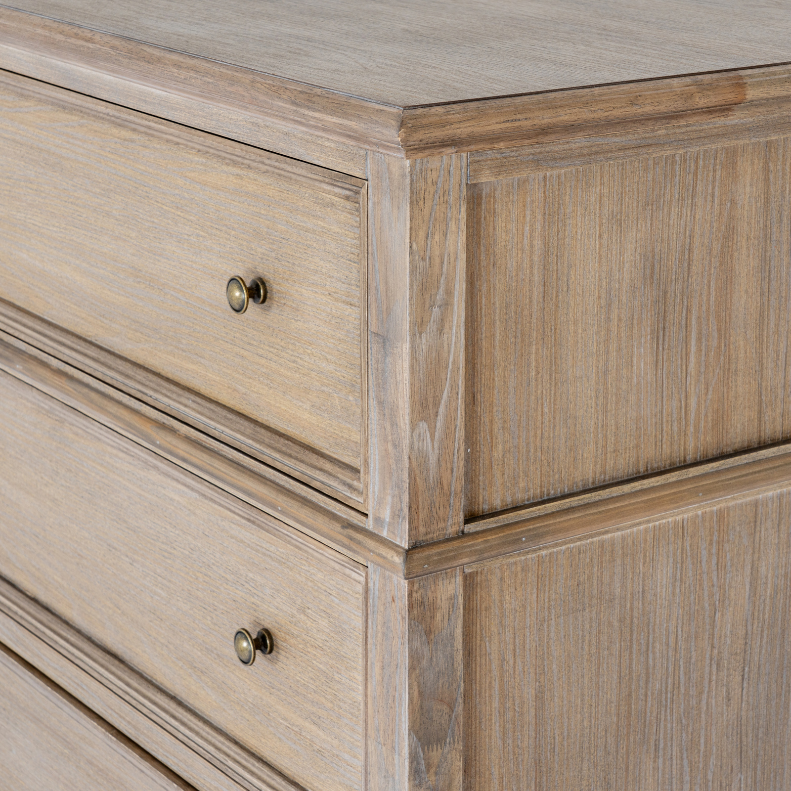 The image shows a chest of drawers, looking at the corner of the side and front, with two drawers and their handles visible as well as part of the top