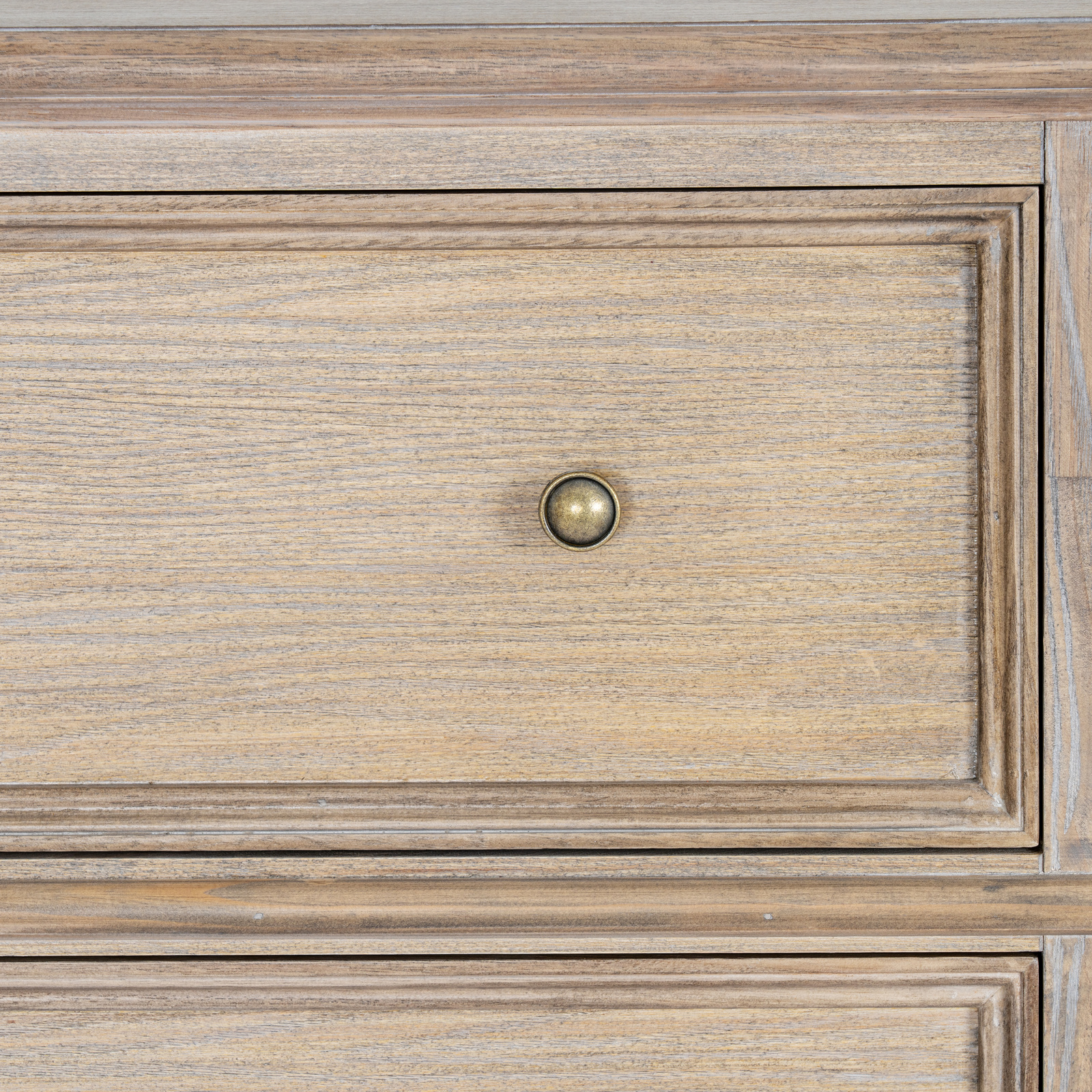 The image shows the front view of a wooden drawer with a small, round brass door handle