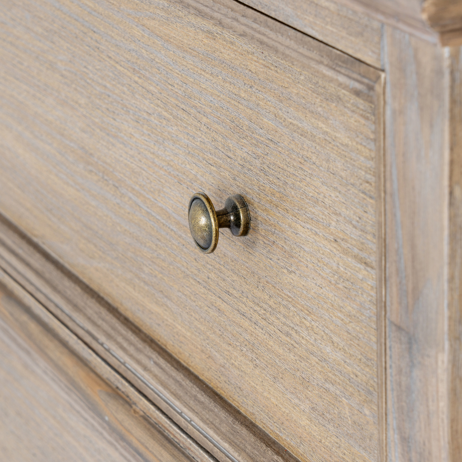 The image shows and angled front view of a wooden drawer with a small, round brass door handle
